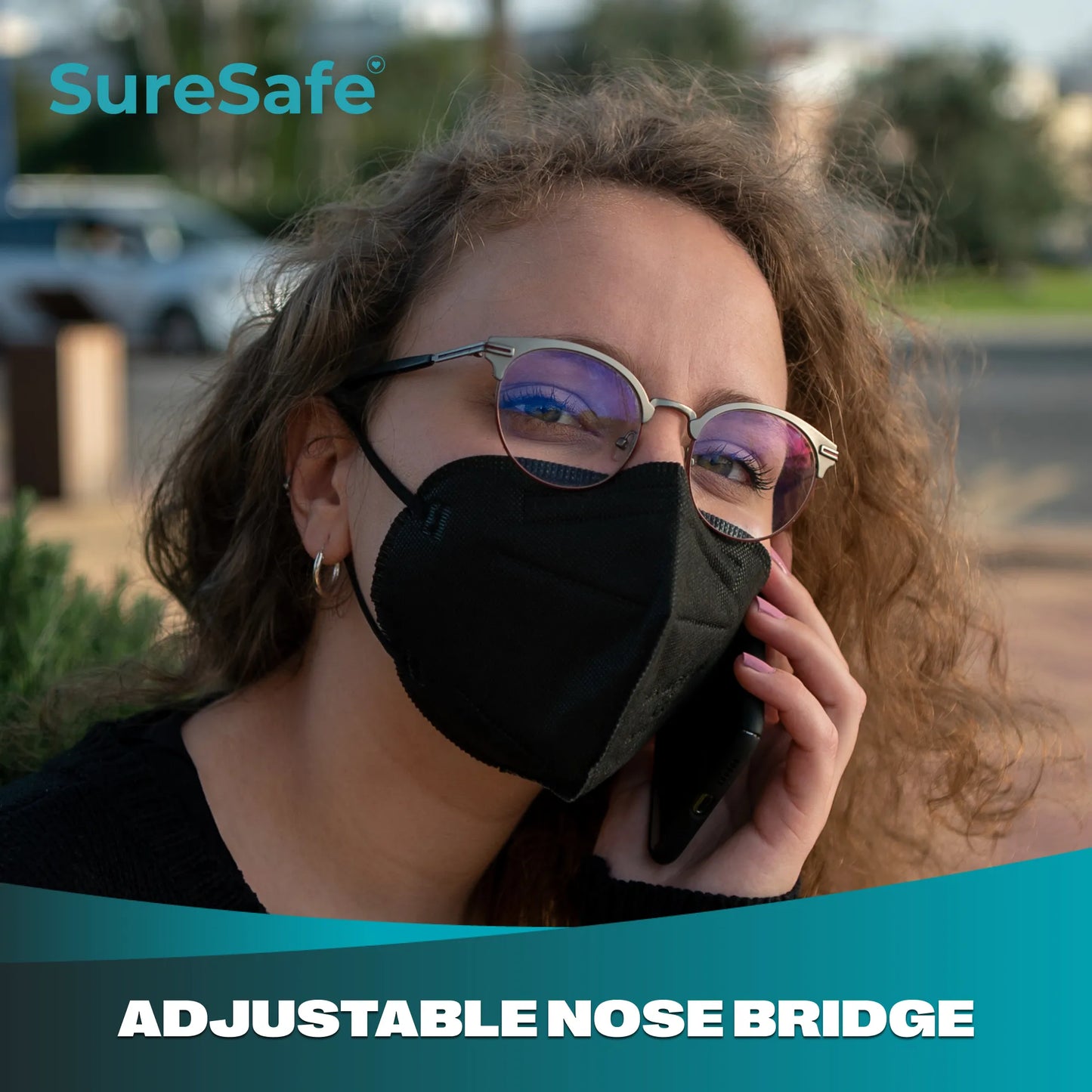 Person using a smartphone while wearing a black SureSafe mask with a secure adjustable nose bridge fit.