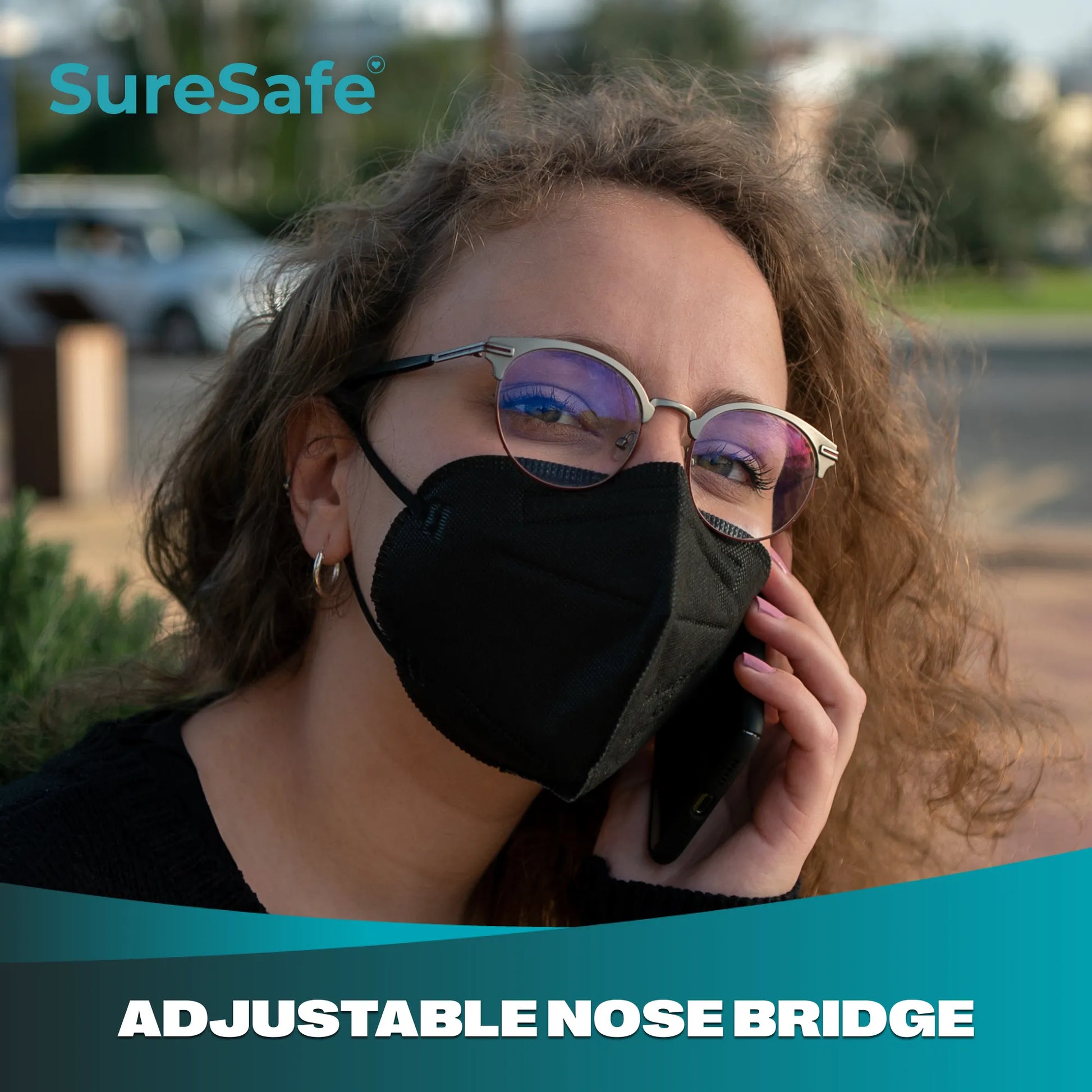 Person using a smartphone while wearing a black SureSafe mask with a secure adjustable nose bridge fit.