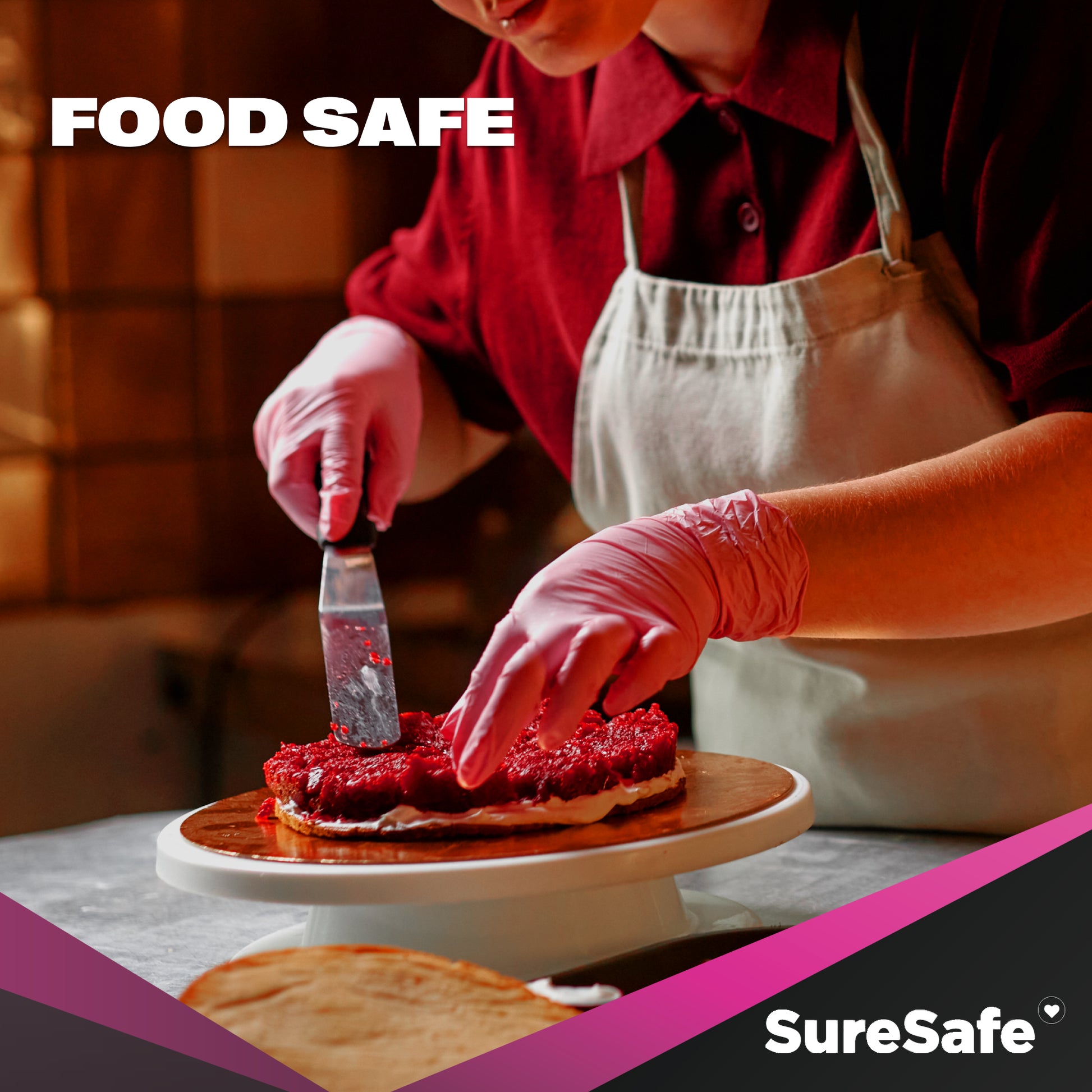Person wearing food-safe pink SureSafe ROSÉ gloves while decorating a cake in a professional bakery.