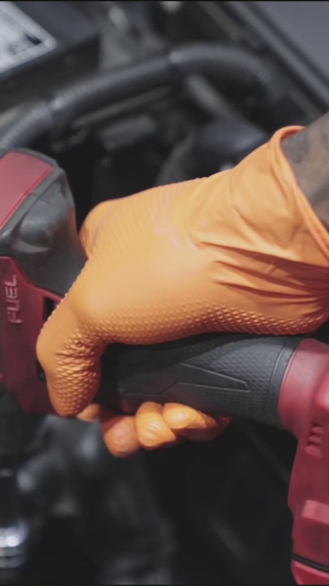 Mechanic using SureSafe Infinity Grip orange nitrile gloves with diamond texture for automotive and engine work.
