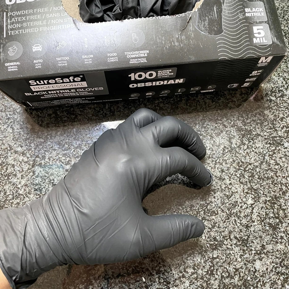 Professional mechanic wearing SureSafe Obsidian black 5 mil nitrile gloves for automotive garage and shop work.